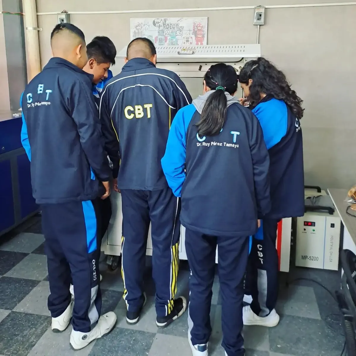 Estudiantes de bachillerato tecnológico observando una máquina de corte láser durante un taller